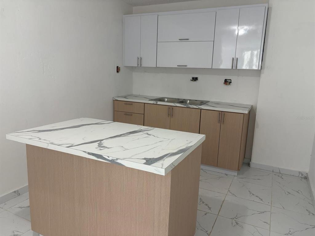 A kitchen features light wood cabinets, white upper cabinets, and a marble-patterned island countertop — 198 LOS PICACHOS, LA CUMBRE DEV., SAN JUAN, PR