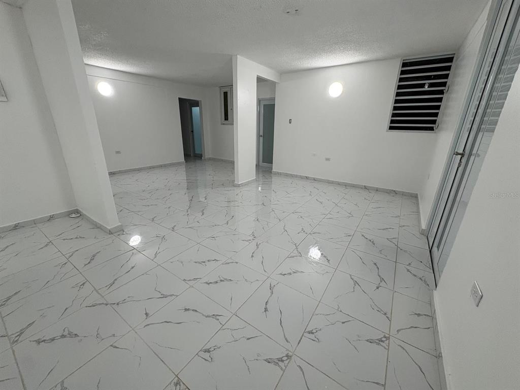 An empty room features white walls, marble-patterned tile flooring, and two circular wall-mounted lights — 198 LOS PICACHOS, LA CUMBRE DEV., SAN JUAN, PR