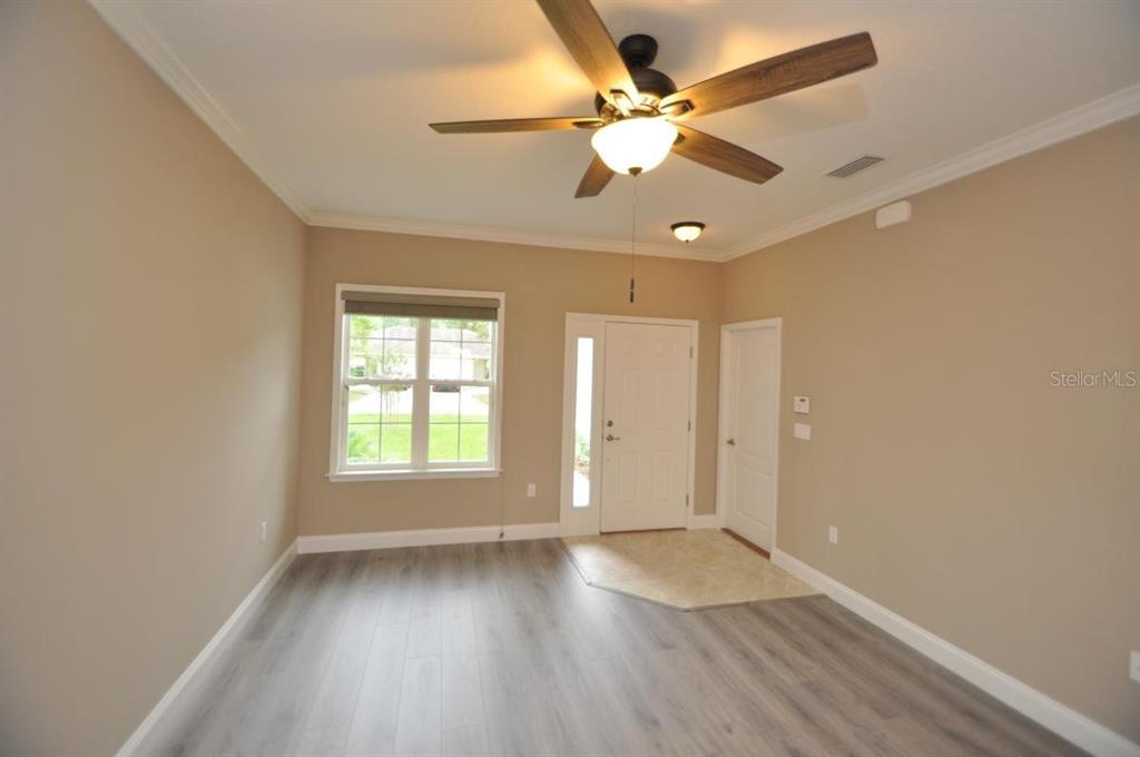 A room with light-colored walls, wood-look flooring, a ceiling fan, and an entryway door — 11 ULLYNN PLACE UNIT B, PALM COAST, FL