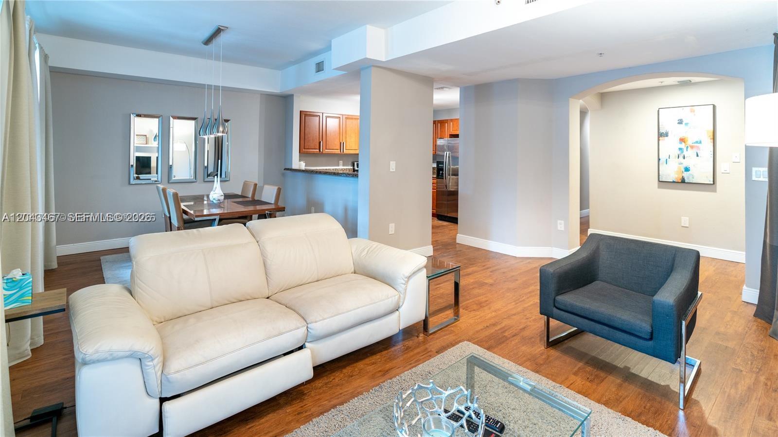 A living room features a white leather sofa, a dark armchair, and a dining area — 11002 NW 83rd St # 106, Doral FL 33178, DORAL, FL