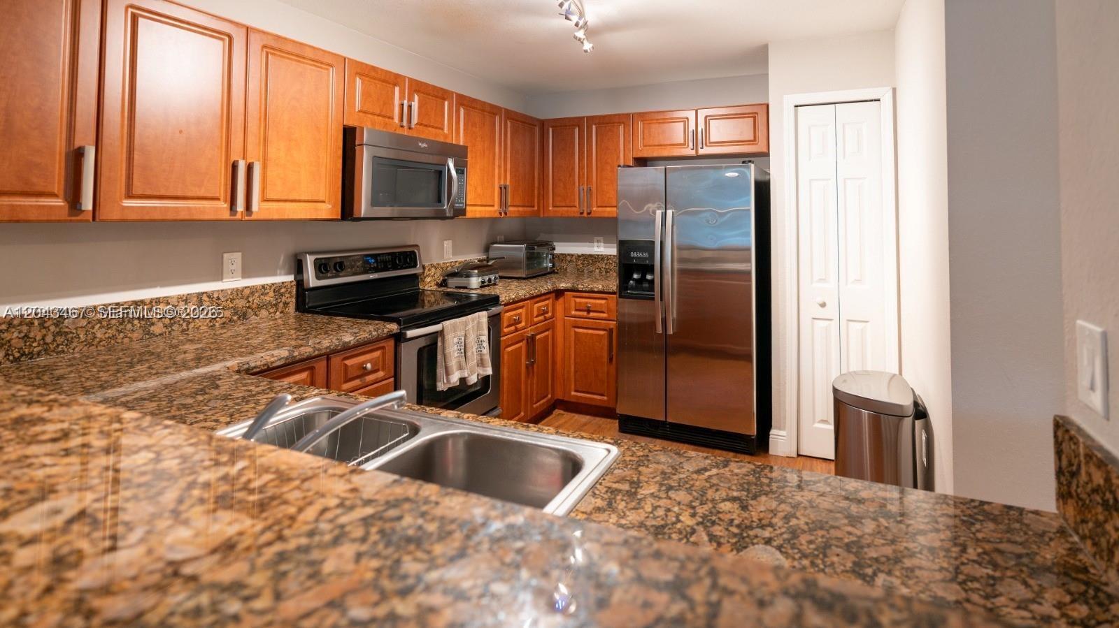 A kitchen features wood cabinets, granite countertops, and stainless steel appliances — 11002 NW 83rd St # 106, Doral FL 33178, DORAL, FL