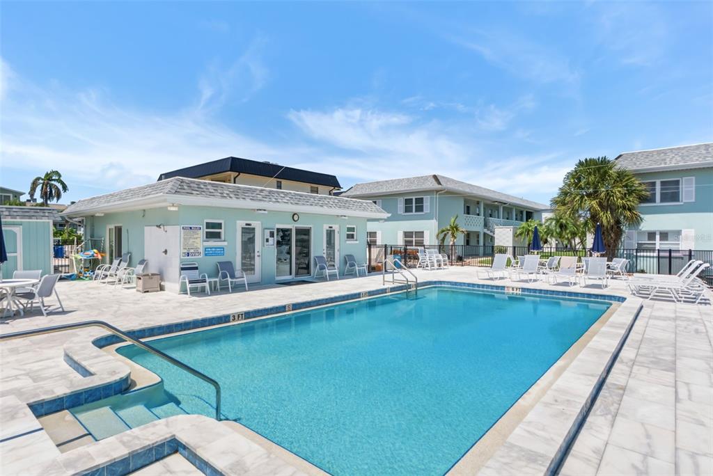 An outdoor swimming pool with a shallow entry area sits beside a light-colored building — 611 GULF DRIVE N UNIT C27, BRADENTON BEACH, FL