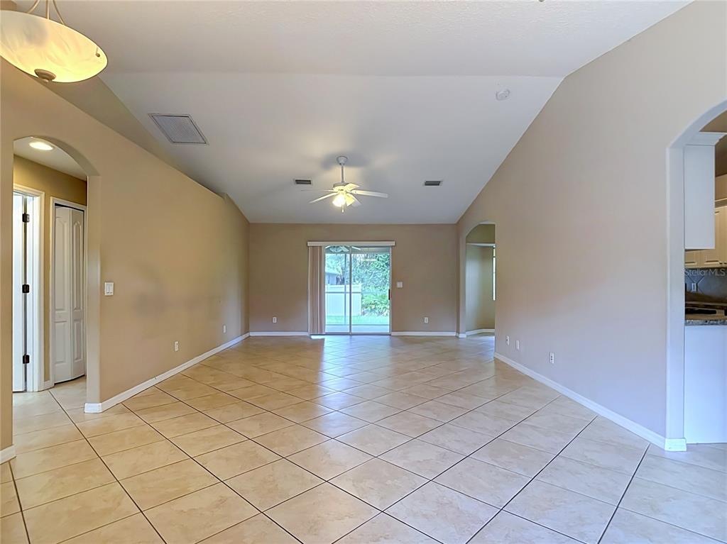 An empty living room features beige walls, a vaulted ceiling, and diagonal tile flooring — 4523 BUTTERFLY LANE, NORTH PORT, FL