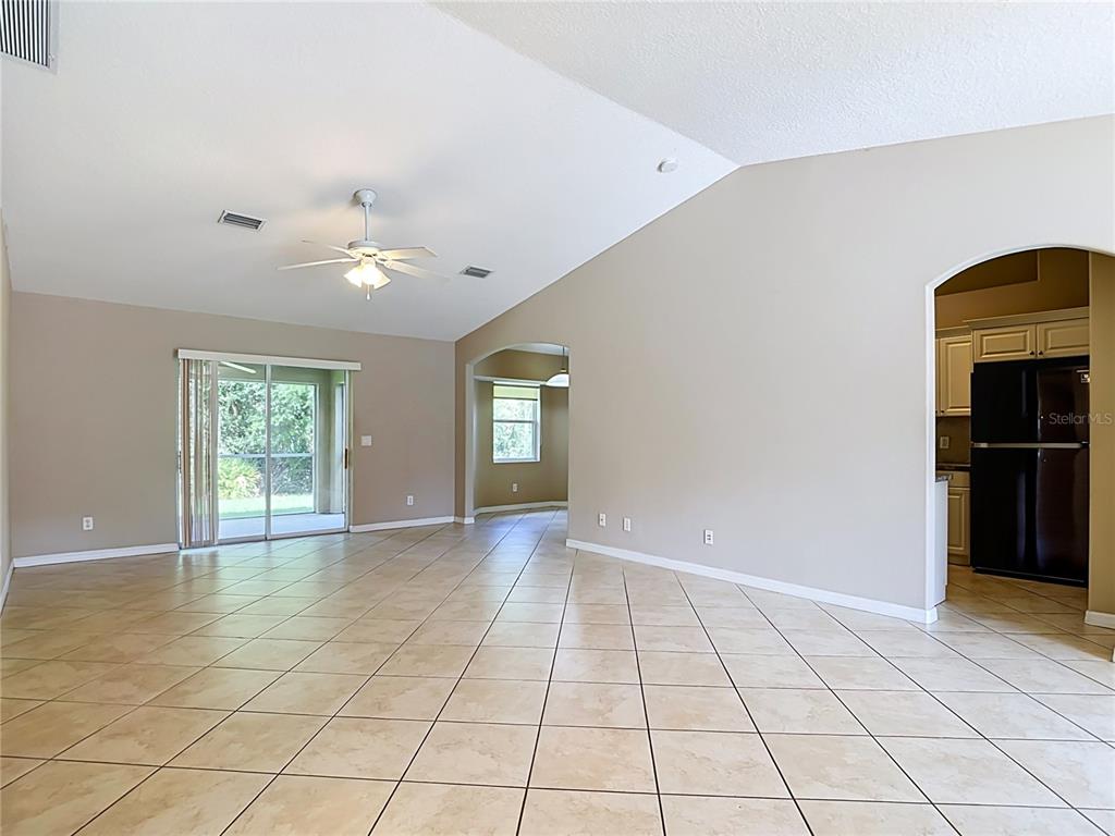 A spacious living area features beige tile flooring, a vaulted ceiling, and an arched kitchen entrance — 4523 BUTTERFLY LANE, NORTH PORT, FL