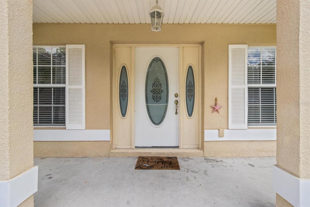 A front porch features a white door with glass inserts, side windows, and shutters — 16038 MALDEN ROAD, WEEKI WACHEE, FL