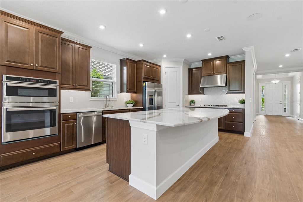 A kitchen features dark wood cabinets, stainless steel appliances, and a white marble-topped island — 29306 GINNETTO DRIVE, WESLEY CHAPEL, FL