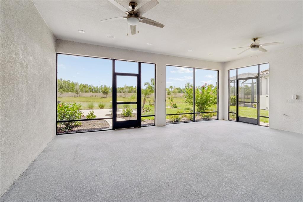 A spacious, covered screened-in patio with a concrete floor, two ceiling fans, and outdoor views — 29306 GINNETTO DRIVE, WESLEY CHAPEL, FL