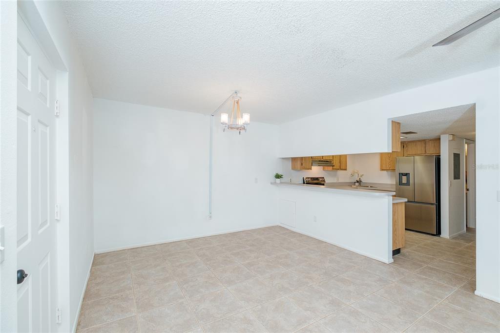 An open dining area with tile flooring leads to a kitchen with stainless steel appliances — 1515 FORREST NELSON BOULEVARD UNIT P101, PORT CHARLOTTE, FL