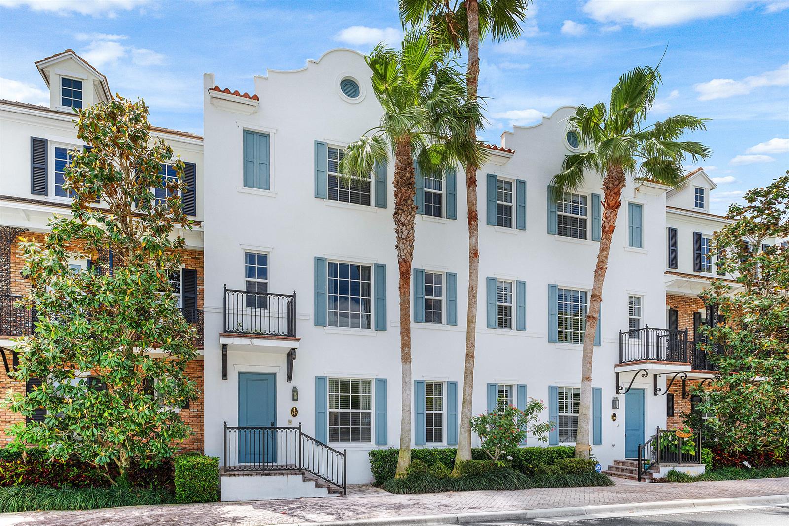 A white three-story townhouse with blue shutters and palm trees in front — 147 N Cannery Row Circle, Delray Beach FL 33444, DELRAY BEACH, FL