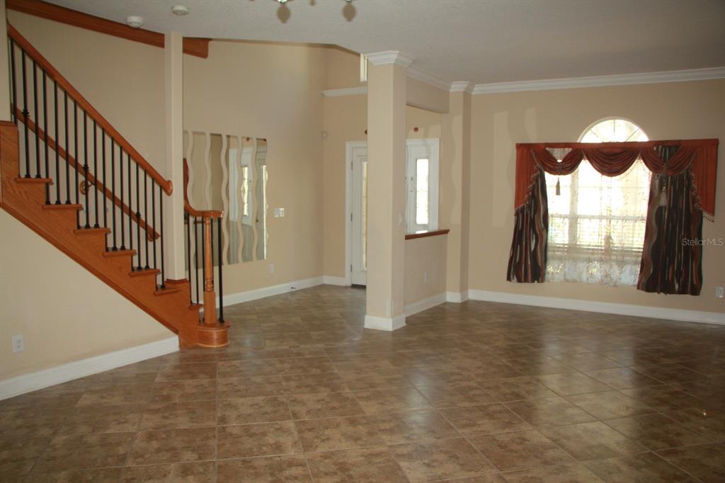 A tiled entryway features a wooden staircase with black railings and a large arched window — 6935 BRESCIA WAY, ORLANDO, FL