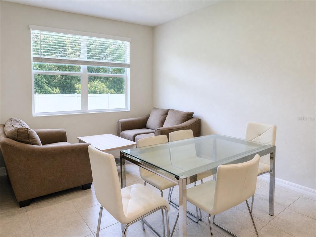 A room features a glass dining table with white chairs and a brown sofa set — 1622 WAY OF PEACE LANE, MASCOTTE, FL