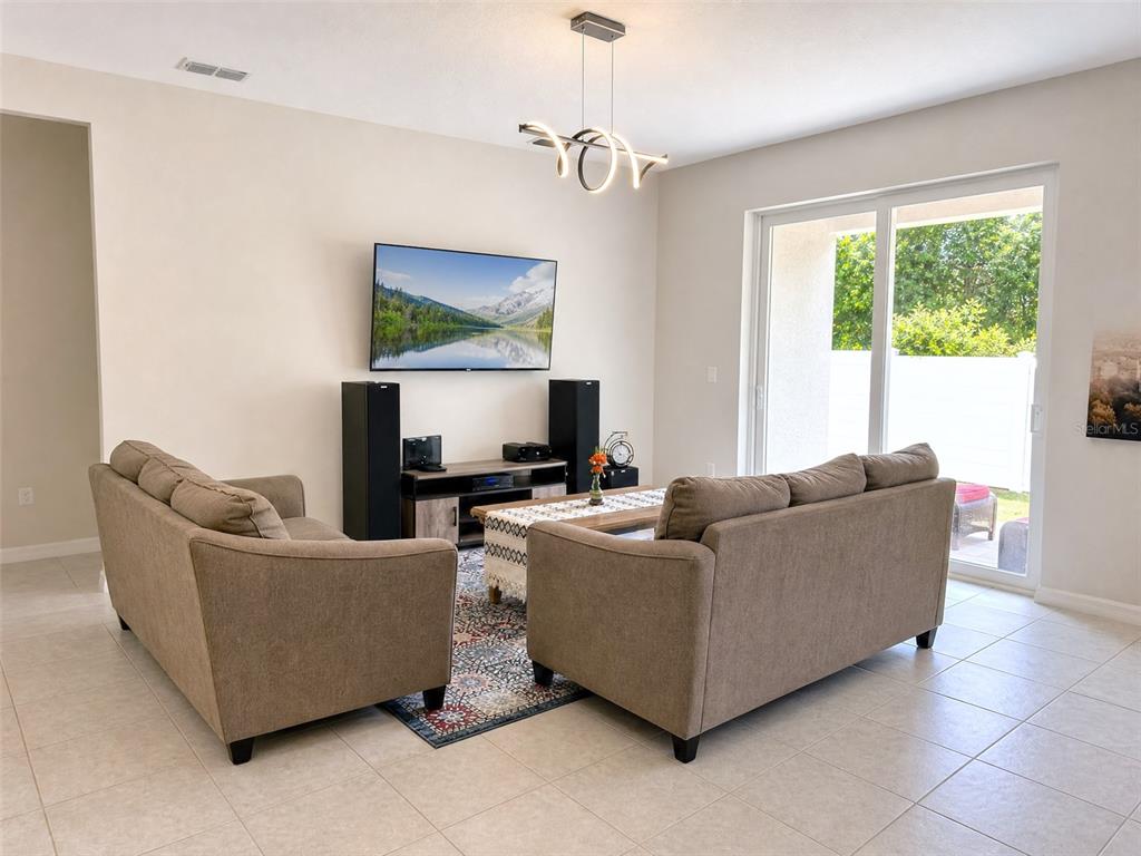 A living room features two beige sofas, a television, and a sliding glass door — 1622 WAY OF PEACE LANE, MASCOTTE, FL