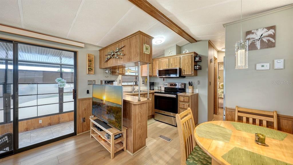 A kitchen with wood cabinets and stainless steel appliances opens to a dining area — 1475 FLAMINGO DRIVE UNIT 71, ENGLEWOOD, FL