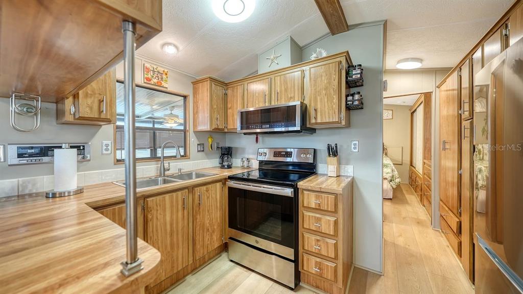 A kitchen features wood cabinets, stainless steel appliances, and wood-look flooring — 1475 FLAMINGO DRIVE UNIT 71, ENGLEWOOD, FL