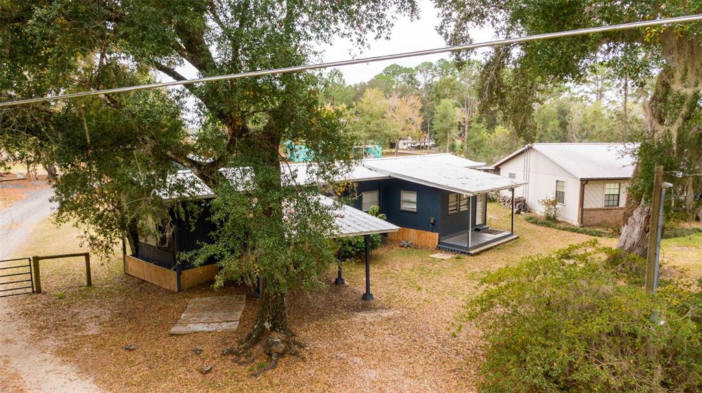 An elevated view shows a dark blue house with a metal roof and attached carport — 21162 NE 146TH PLACE, SALT SPRINGS, FL