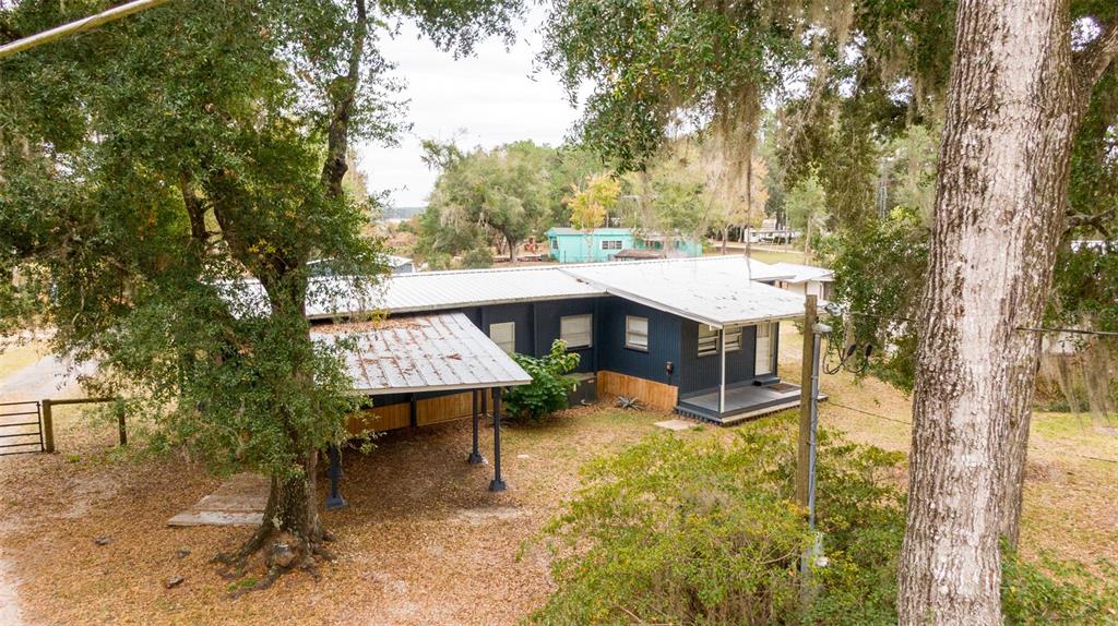 An elevated view of a dark blue house with a metal roof and attached carport — 21162 NE 146TH PLACE, SALT SPRINGS, FL