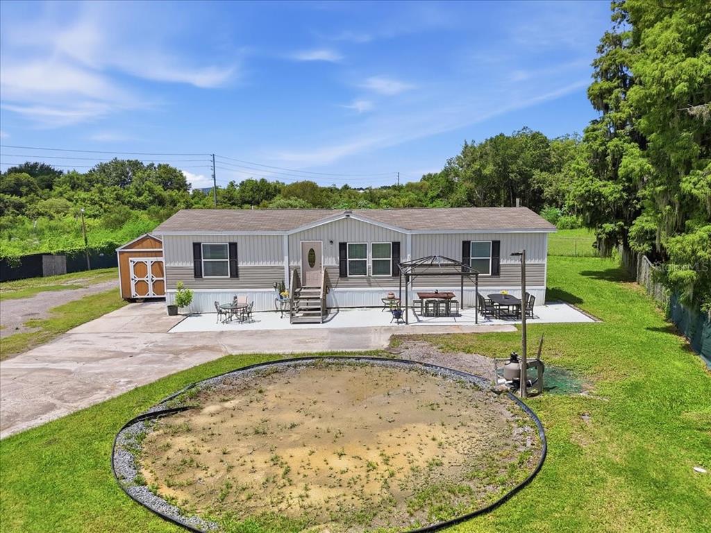 An exterior view of a manufactured home with a concrete patio, shed, and circular yard area — 2531 DAWN HEIGHTS DRIVE, LAKELAND, FL