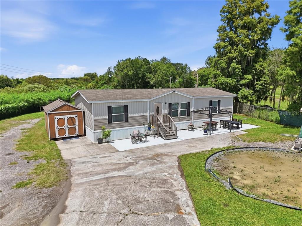 An aerial view of a manufactured home with a shed, concrete patio, and gravel driveway — 2531 DAWN HEIGHTS DRIVE, LAKELAND, FL