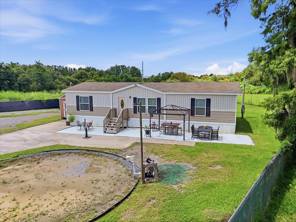 An exterior view of a tan manufactured home with a patio, gazebo, and fenced yard — 2531 DAWN HEIGHTS DRIVE, LAKELAND, FL