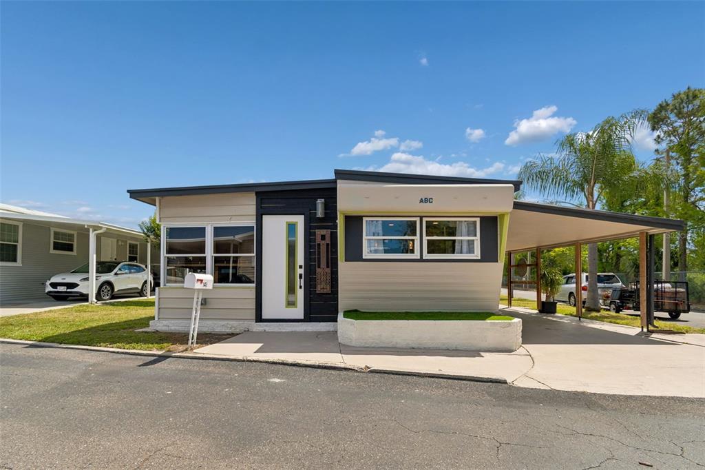 A single-story mobile home with a carport, white door, and a small front planter — 1915 SEMINOLE BOULEVARD UNIT 140, LARGO, FL