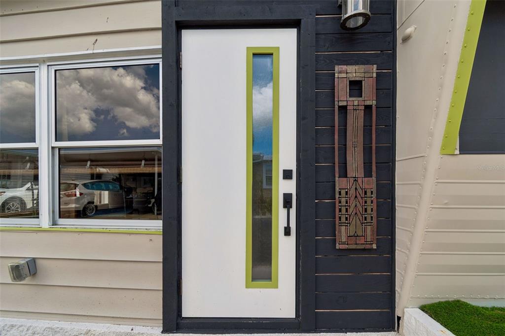 A modern white front door with a lime green frame sits beside dark horizontal siding — 1915 SEMINOLE BOULEVARD UNIT 140, LARGO, FL