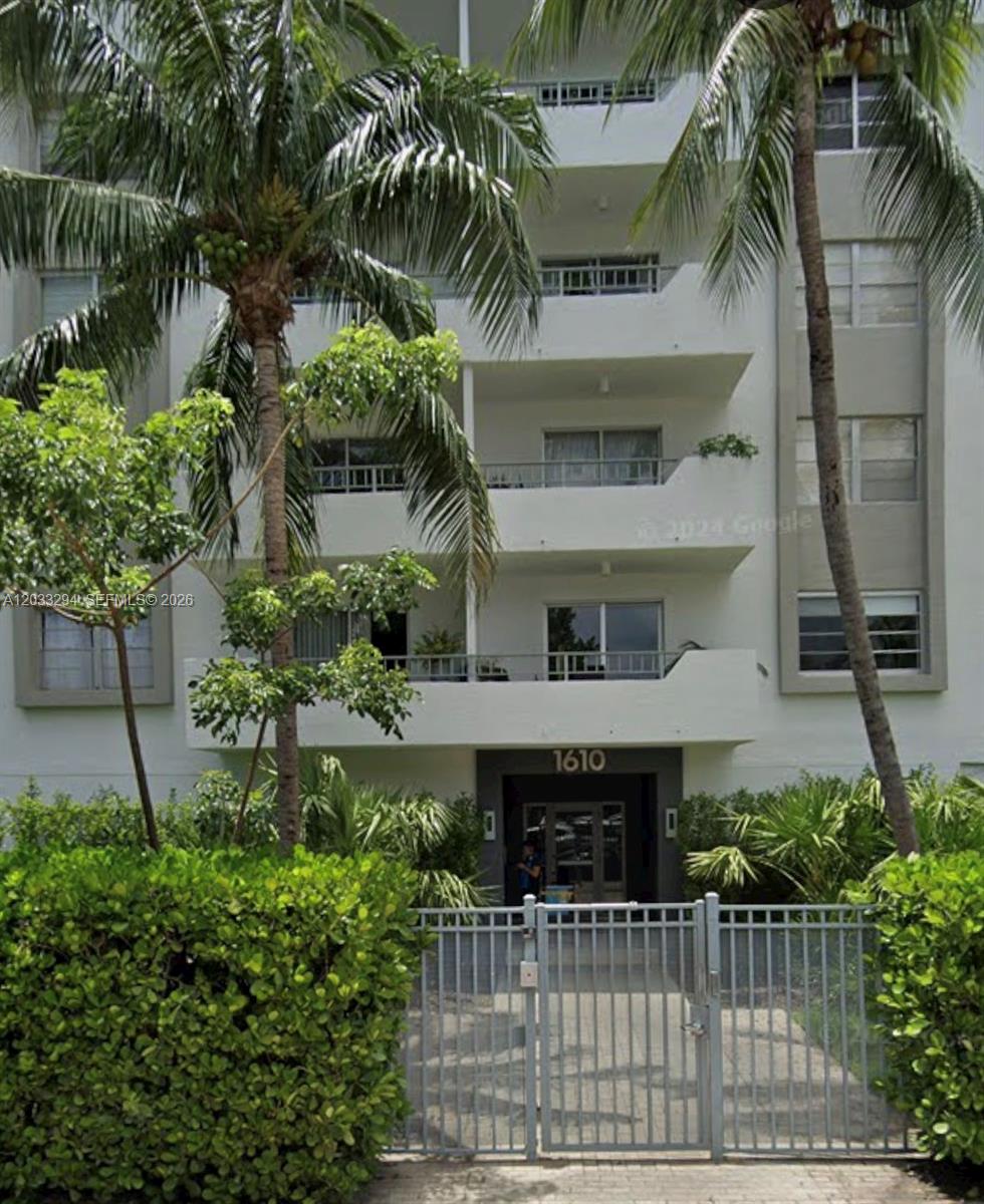 A multi-story white apartment building with balconies and palm trees behind a gated entrance — 1610 Lenox Ave # 412, Miami Beach FL 33139, MIAMI BEACH, FL