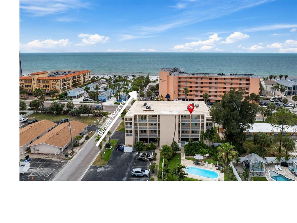 An aerial view shows a multi-story apartment building with a pool and nearby beach access — 1005 GULF BOULEVARD UNIT 10, INDIAN ROCKS BEACH, FL