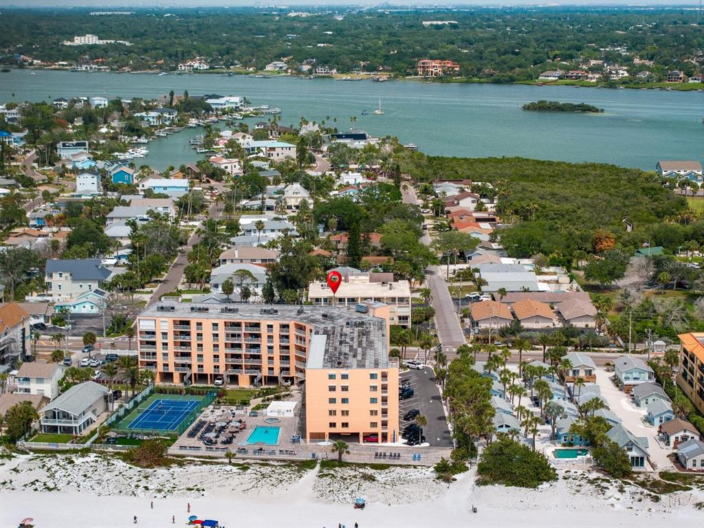 An aerial view of a multi-story peach-colored apartment building located on a sandy beach — 1005 GULF BOULEVARD UNIT 10, INDIAN ROCKS BEACH, FL