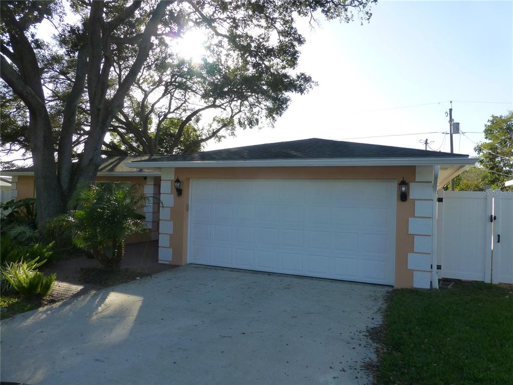 A single-story house features a two-car garage, a concrete driveway, and a large oak tree — 752 PATRICIA AVENUE, DUNEDIN, FL