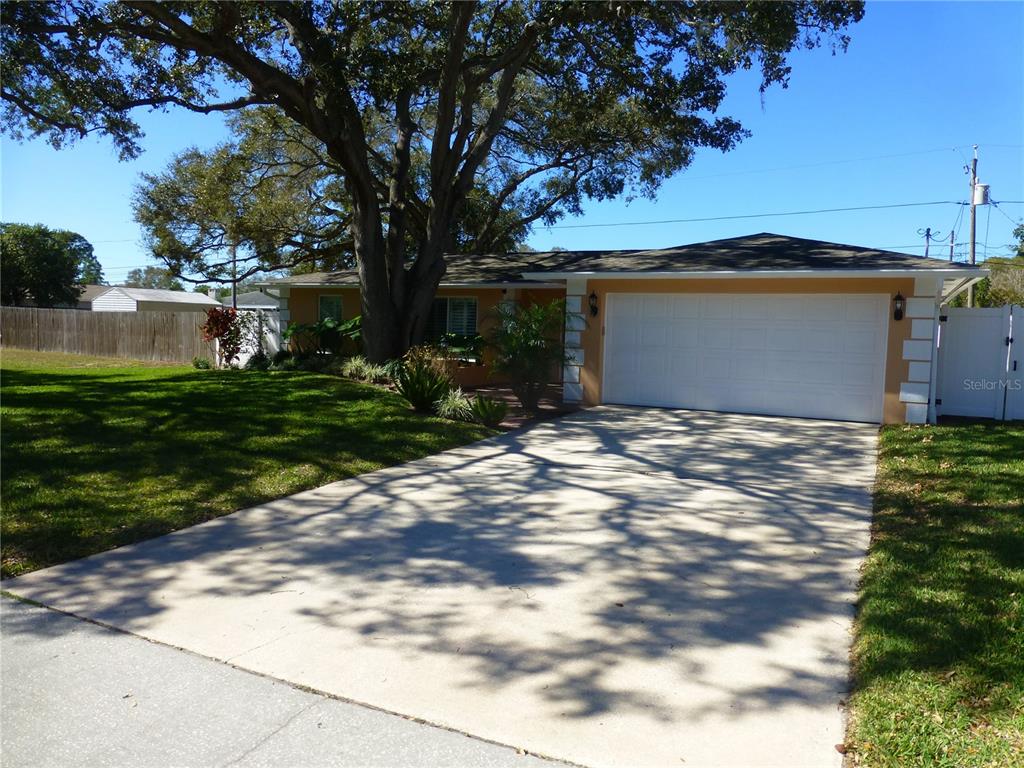 A single-story house with a two-car garage, a large tree, and a concrete driveway — 752 PATRICIA AVENUE, DUNEDIN, FL