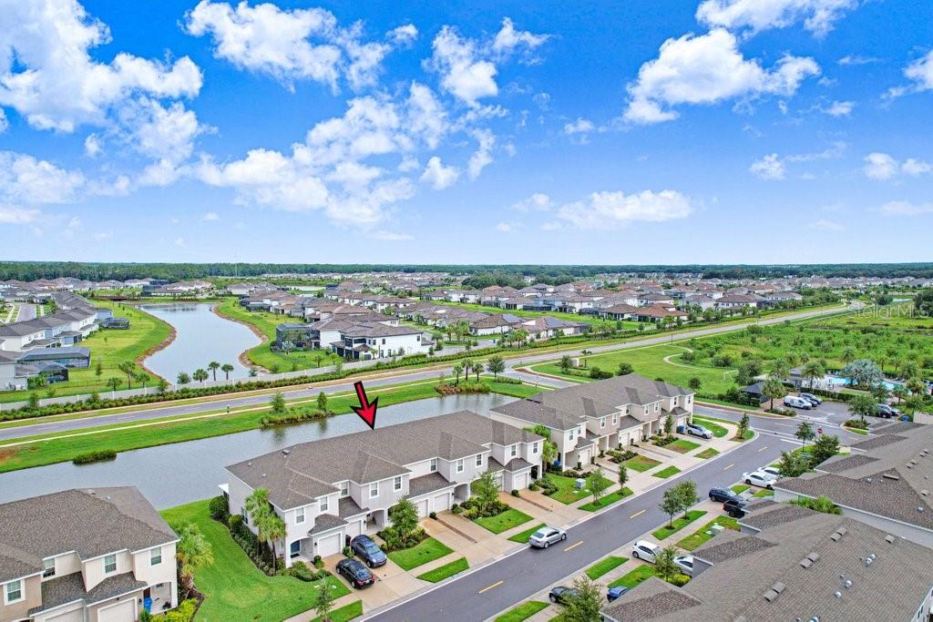 An aerial view of a multi-unit townhouse building situated next to a small pond — 2301 ALEE LANE, WESLEY CHAPEL, FL