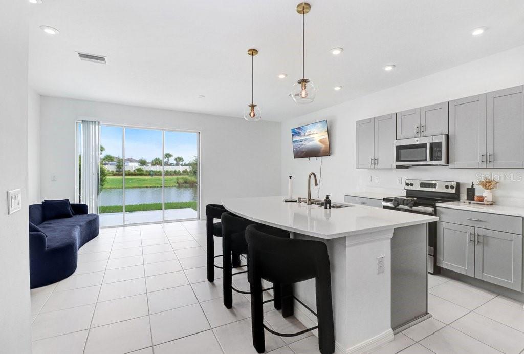 A modern kitchen with gray cabinets, a white island, and a view of a pond — 2301 ALEE LANE, WESLEY CHAPEL, FL