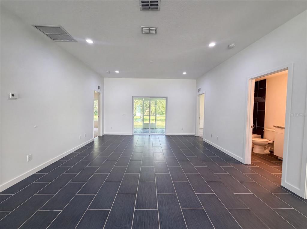 A spacious room with dark rectangular floor tiles, white walls, recessed lighting, and sliding doors — 2840 S SHADE AVENUE, SARASOTA, FL