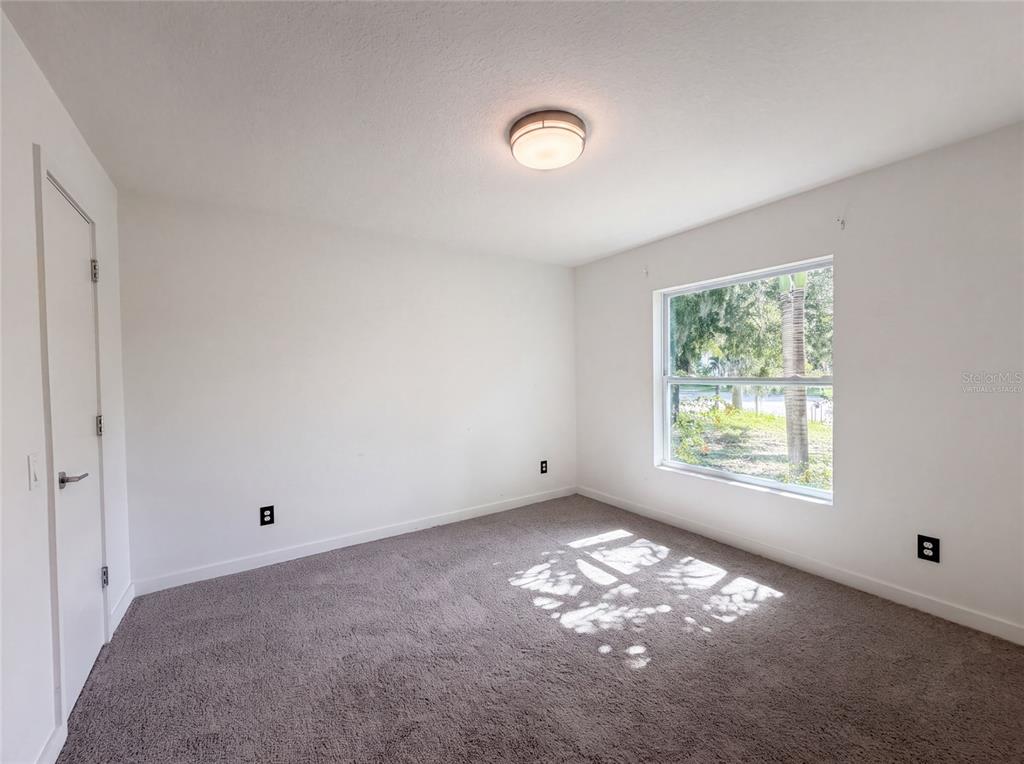 An empty bedroom with white walls, gray carpeting, a single window, and a ceiling light — 2840 S SHADE AVENUE, SARASOTA, FL