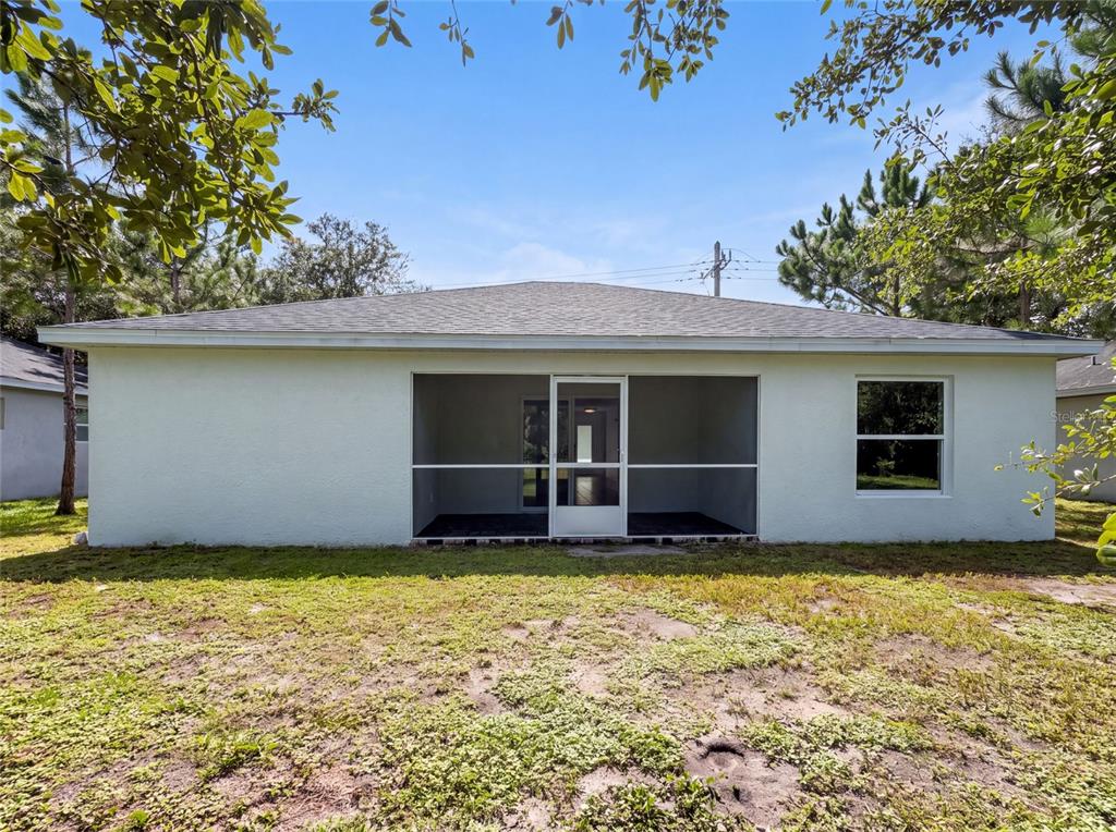 The back exterior of a house features a screened-in porch and a single window — 2840 S SHADE AVENUE, SARASOTA, FL