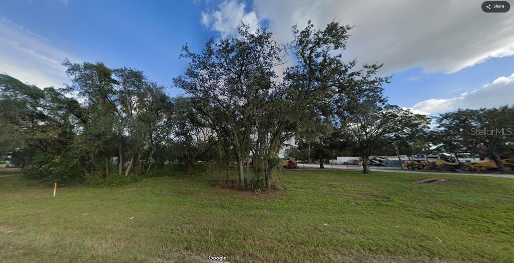 A grassy lot features several large, mature trees under a partly cloudy sky — N/A, POLK CITY, FL