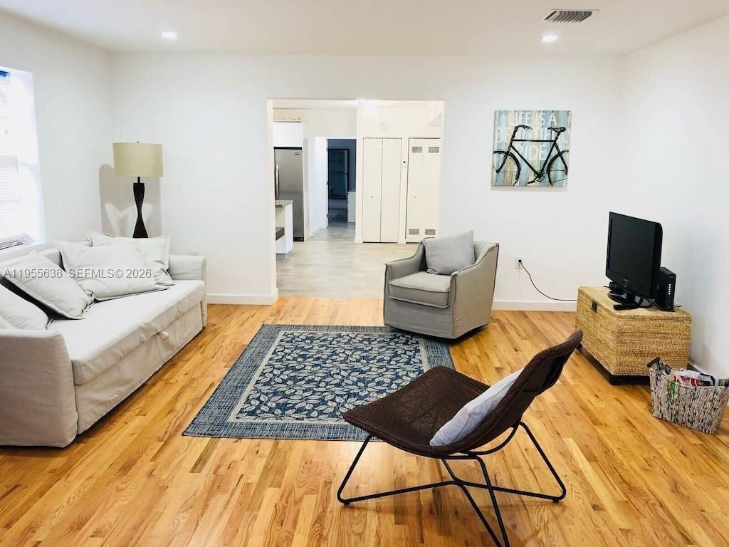 A living room features light hardwood floors, a sofa, two chairs, and a television — 2375 NE 185th St, Miami FL 33180, MIAMI, FL
