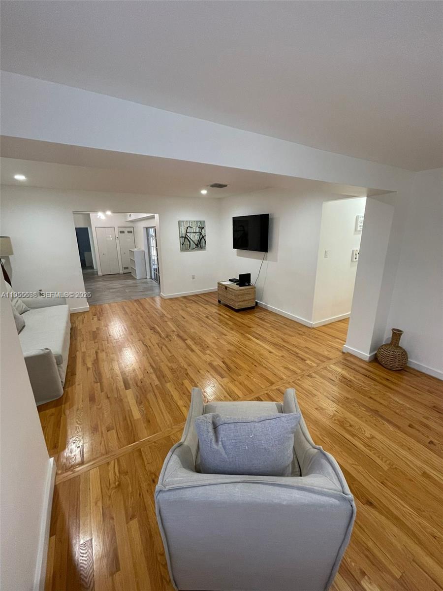 A living room features light hardwood floors, white walls, a mounted television, and neutral furniture — 2375 NE 185th St, Miami FL 33180, MIAMI, FL