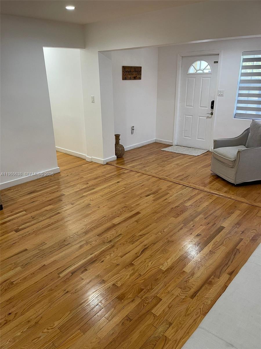 A living room features hardwood floors, a white front door, and a light gray armchair — 2375 NE 185th St, Miami FL 33180, MIAMI, FL