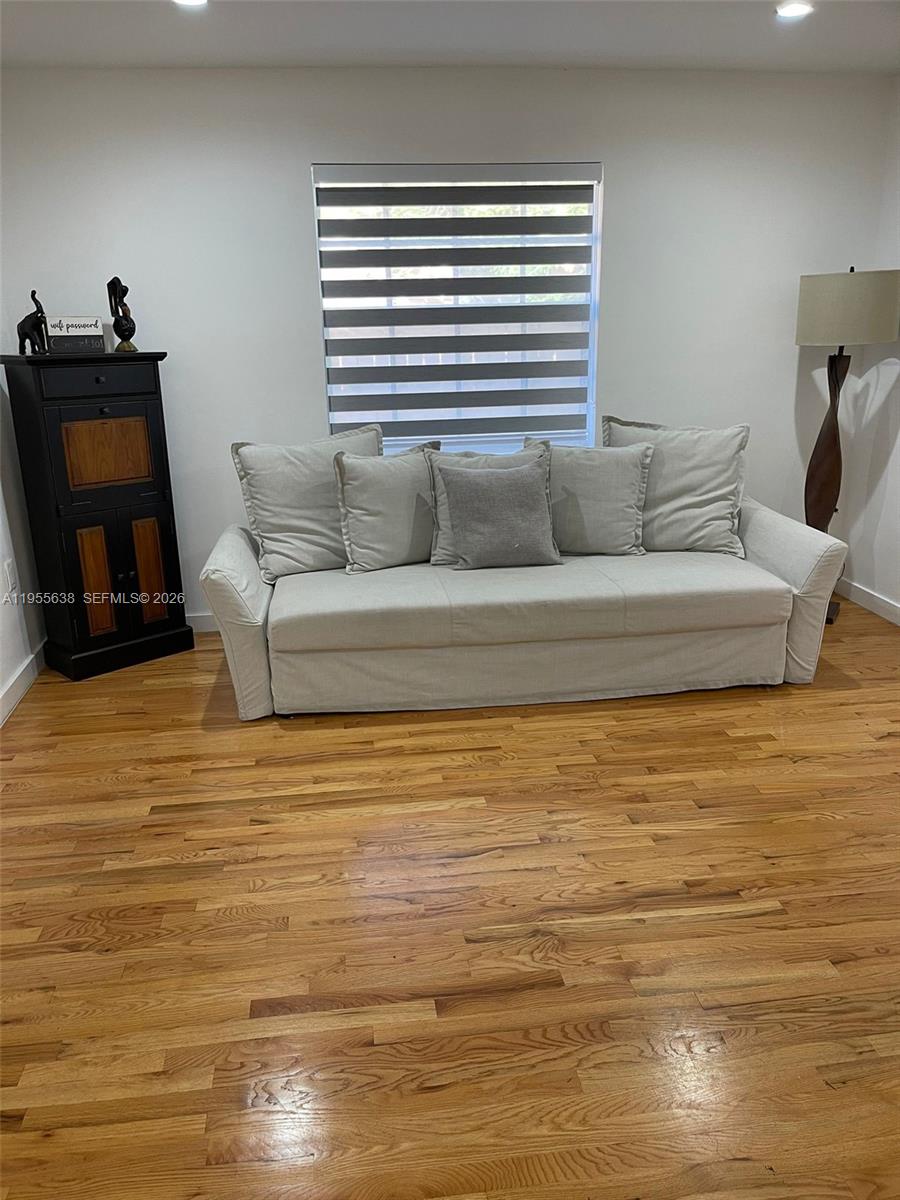 A living room features a light-colored sofa, a black cabinet, and hardwood flooring — 2375 NE 185th St, Miami FL 33180, MIAMI, FL