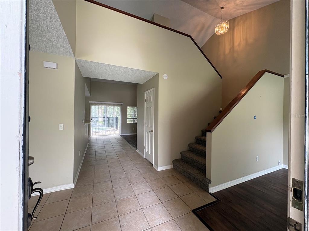 An entryway features tiled flooring, a carpeted staircase with a wooden railing, and a sliding door — 7126 YARDLEY WAY, TAMPA, FL