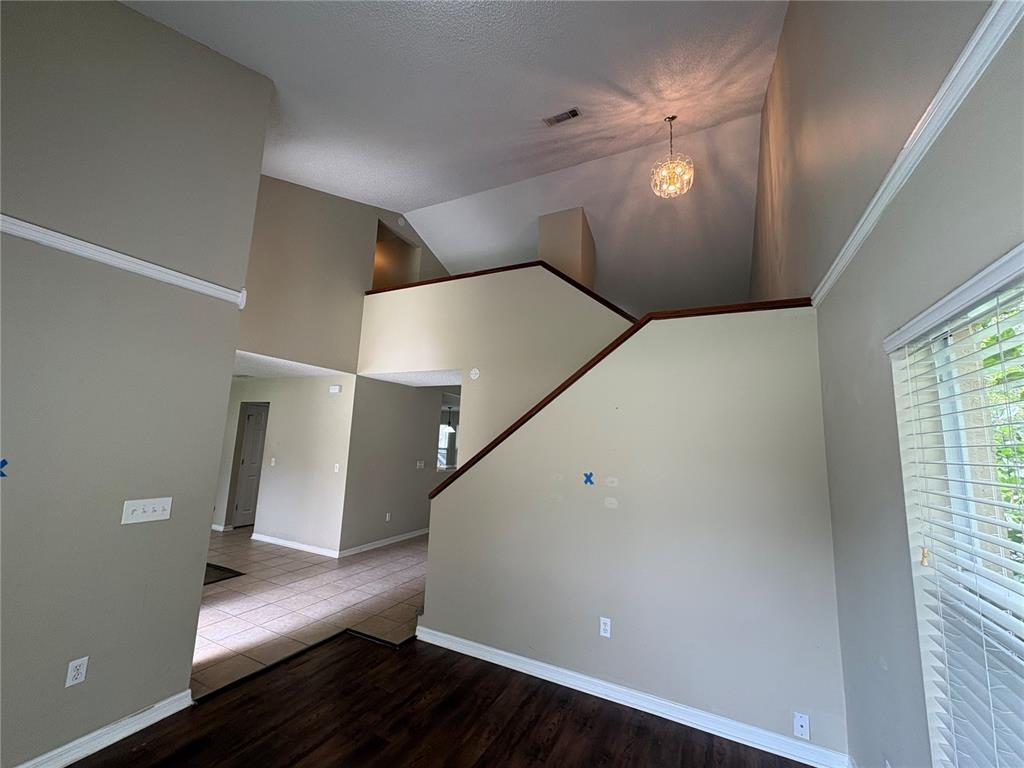 A living area with high vaulted ceilings, a staircase, and a view into an adjacent room — 7126 YARDLEY WAY, TAMPA, FL