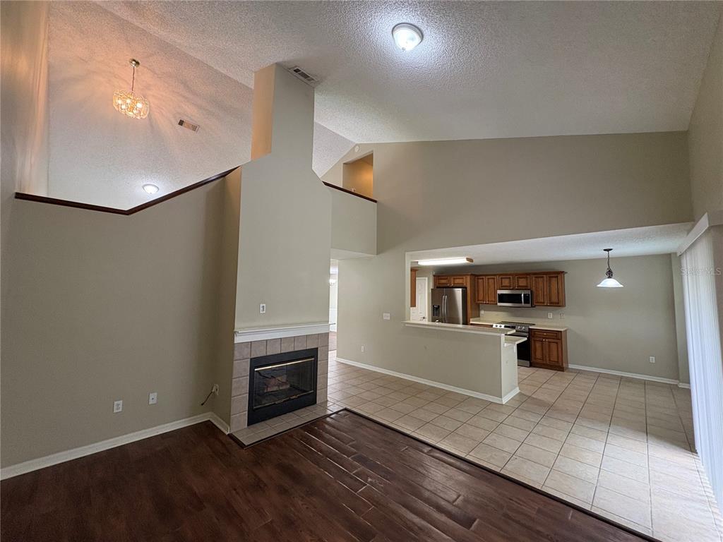 A living room with a fireplace and vaulted ceilings opens to a tiled kitchen area — 7126 YARDLEY WAY, TAMPA, FL