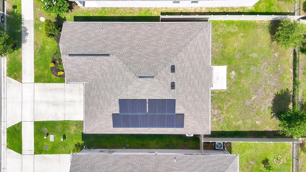 An aerial view shows a house roof with solar panels and a fenced backyard — 839 OFANTO WAY, HAINES CITY, FL