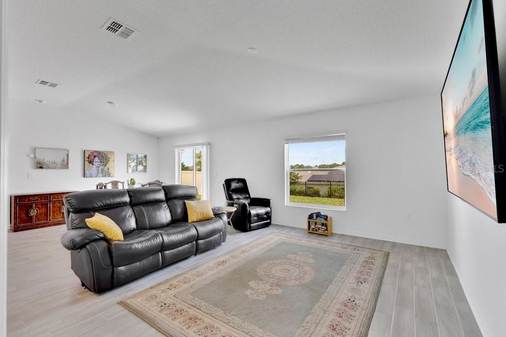 A living room features a black leather sofa, a recliner, and a large wall-mounted television — 839 OFANTO WAY, HAINES CITY, FL