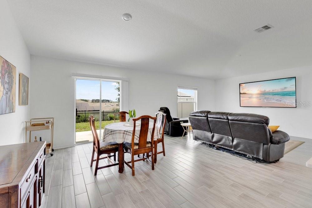 A bright living and dining area with tile floors, a sliding glass door, and furniture — 839 OFANTO WAY, HAINES CITY, FL