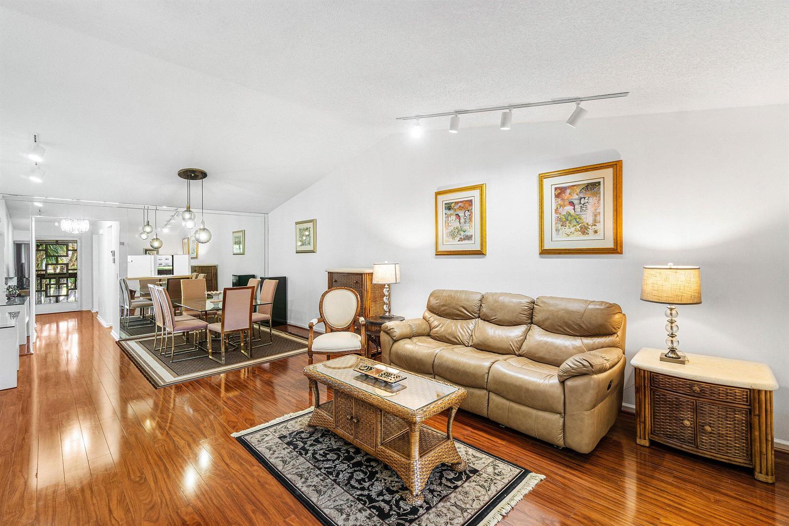 A living room and dining area with hardwood floors, a tan leather sofa, and mirrors — 10137 Mangrove Drive # 203, Boynton Beach FL 33437, BOYNTON BEACH, FL