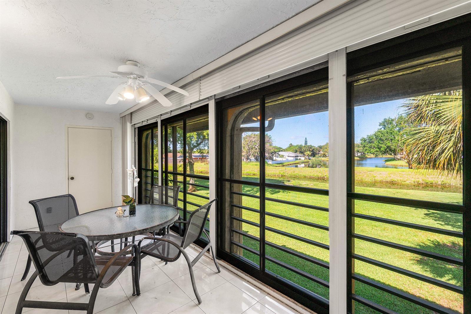 A sunroom with a dining set, tile floors, and large windows overlooking a grassy yard — 10137 Mangrove Drive # 203, Boynton Beach FL 33437, BOYNTON BEACH, FL