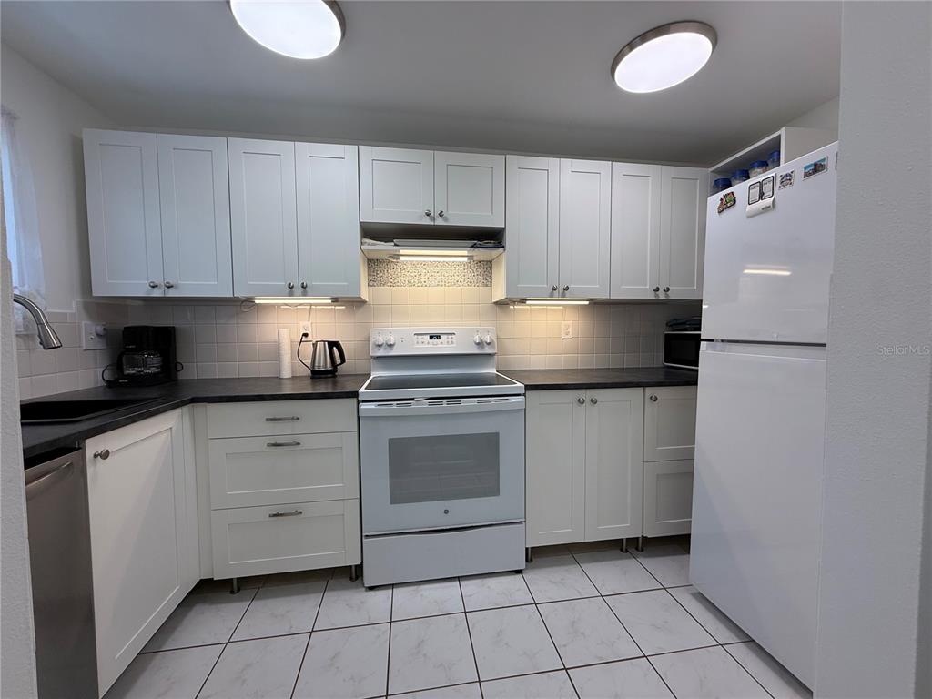 A kitchen features white cabinets, a white stove, a white refrigerator, and tiled flooring — 1243 S MARTIN LUTHER KING JR AVENUE UNIT C303, CLEARWATER, FL