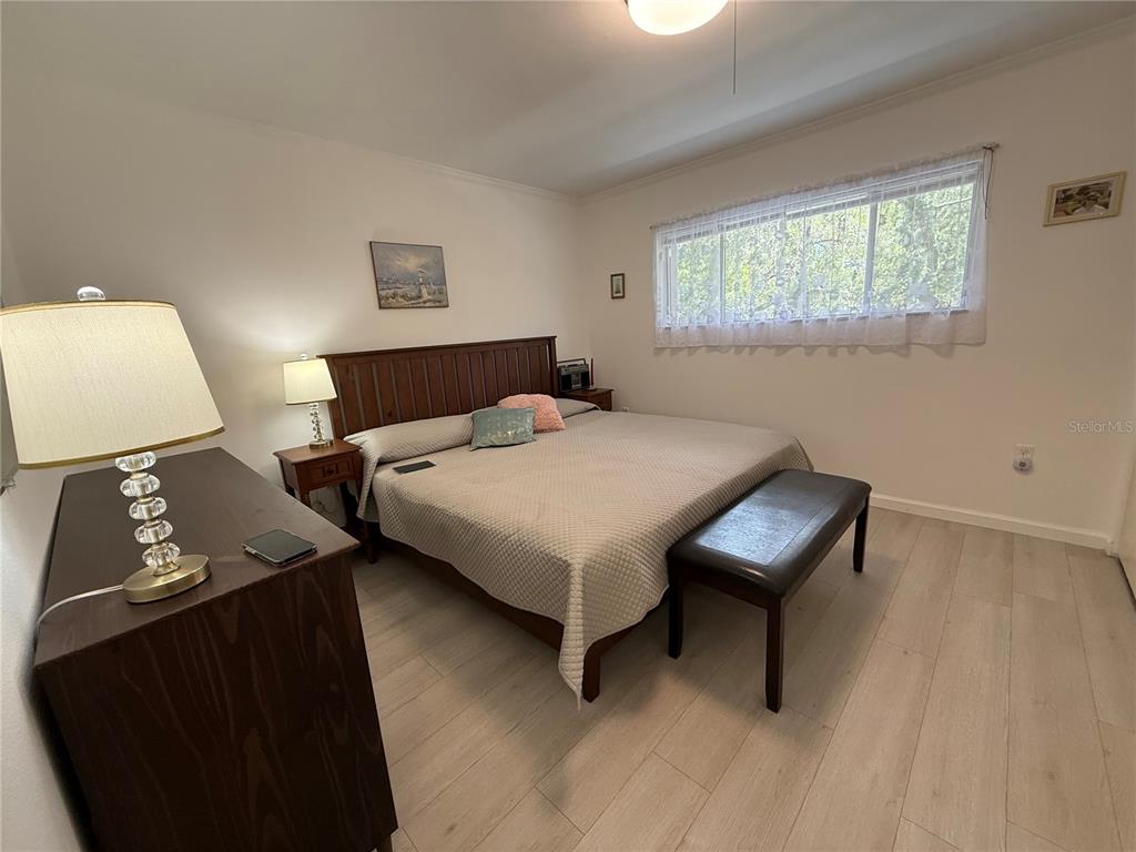 A bedroom features a wooden bed frame, a dark dresser, and light-colored wood flooring — 1243 S MARTIN LUTHER KING JR AVENUE UNIT C303, CLEARWATER, FL